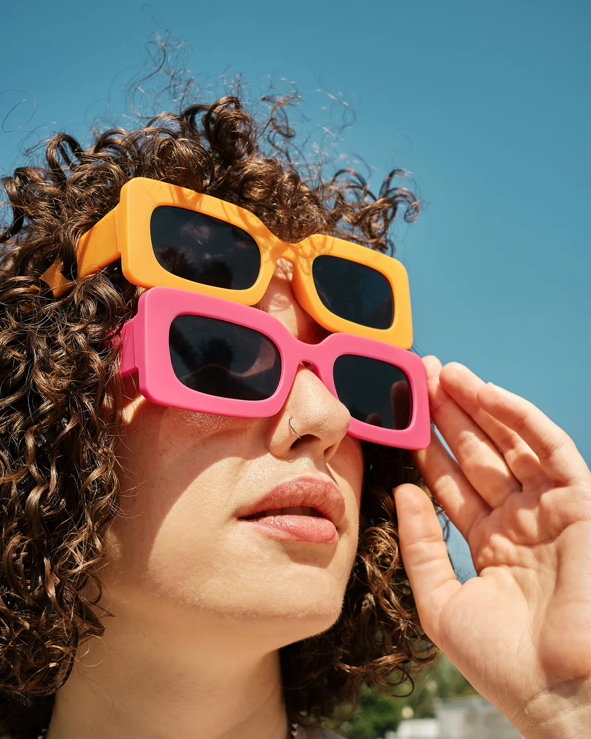 Woman in two pairs of colorful sunglasses
