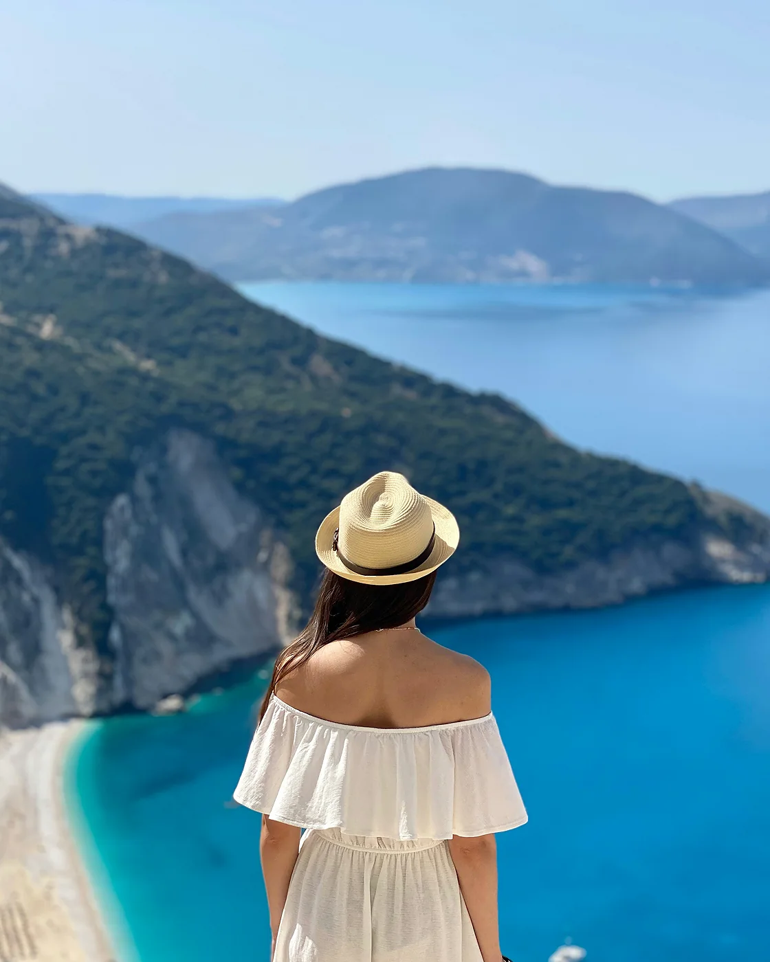 Woman in a sun hat above a turquoise bay