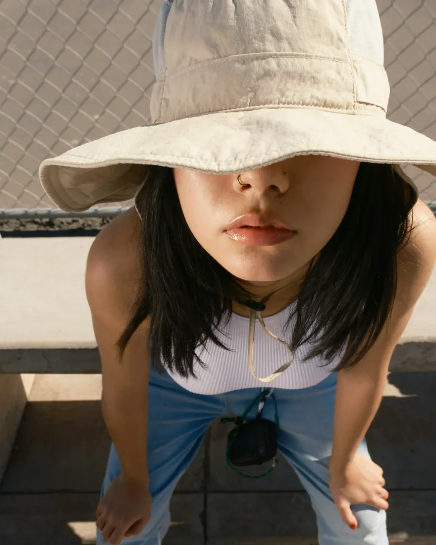 Person in a bucket hat leaning toward the camera