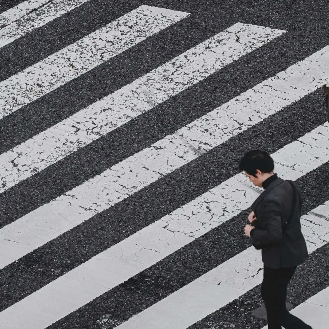 People crossing a striped crosswalk from above