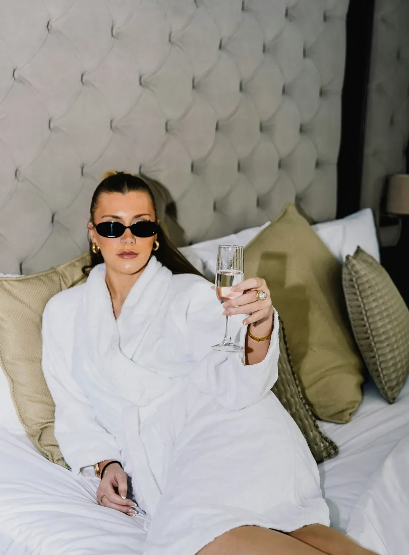Woman in a white robe on a hotel bed